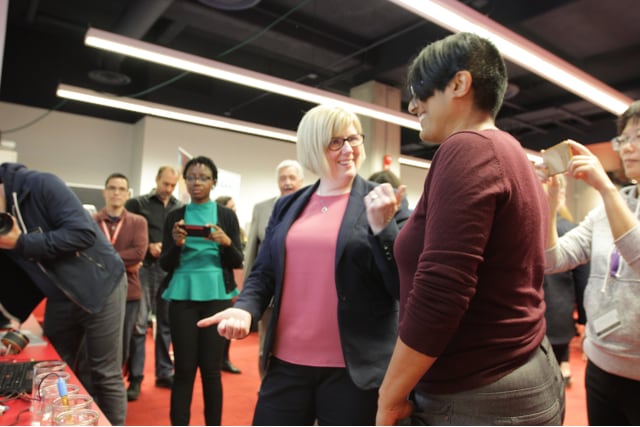 An IDRC team member and visitor smiling and chatting about a project demonstration at an event.